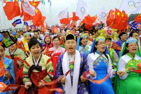 Local people dressed in the ethnic costumes cheer for the 2008 Beijing Olympic Games torch relay in Shenyang, capital of northeast China's Liaoning Province, on July 17, 2008. 