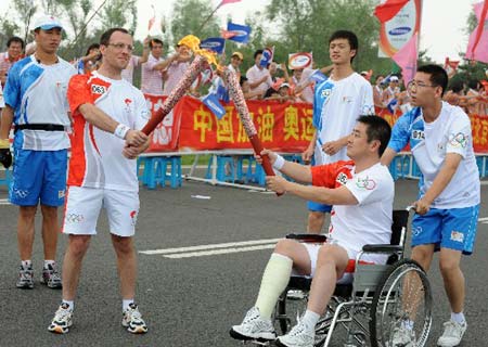 Torchbearer Kang Hui (R-2) lights the torch for the next torchbearer Raga Thomas during the 2008 Beijing Olympic Games torch relay in Shenyang, capital of northeast China's Liaoning Province, on July 17, 2008.