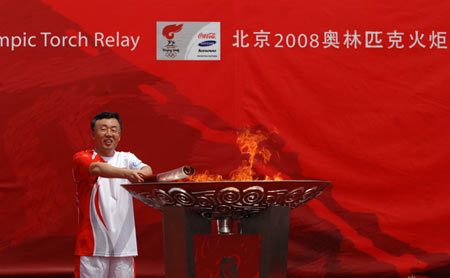 Torchbearer Su Hongzhang lights the cauldron during the 2008 Beijing Olympic Games torch relay in Shenyang, capital of northeast China's Liaoning Province, on July 17, 2008. 