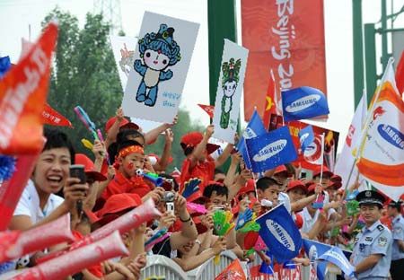 Local residents wave flags to greet the Olympic flame during the 2008 Beijing Olympic Games torch relay in Shenyang, capital of northeast China's Liaoning Province, on July 17, 2008. 