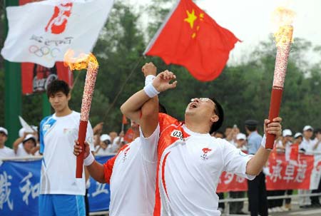 Torchbearer Du Junfeng (R) and torchbearer Du Rongjie pose with torches during the 2008 Beijing Olympic Games torch relay in Shenyang, capital of northeast China's Liaoning Province, on July 17, 2008.