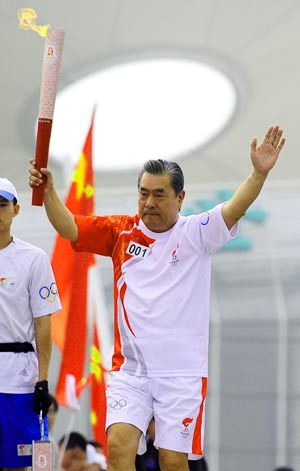 Torchbearer Liu Hongtu, whose father Liu Changchun was China's first Olympian, runs during the 2008 Beijing Olympic Games torch relay in Shenyang, capital of northeast China's Liaoning Province, on July 17, 2008.