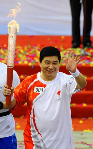 Torchbearer Wang Yifu, head coach of the Chinese national shooting team and the country's most experienced Olympian with six successive appearances from 1984 to 2004, waves during the 2008 Beijing Olympic Games torch relay in Anshan, city of northeast China's Liaoning Province, on July 18, 2008. 
