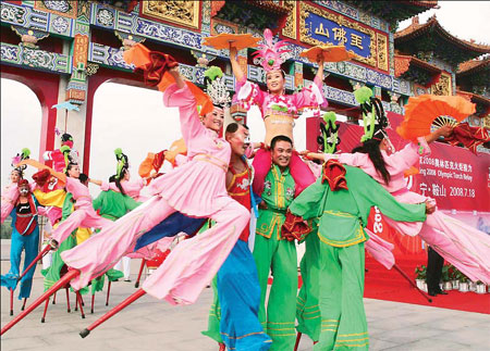 Stilt-walkers and Yangge dancers - a traditional folk dance - entertain the crowds during the torch relay in Anshan, Liaoning province, on Friday. (China News Service)