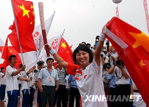 Chinese former athletics Olympics champion Wang Junxia becomes the first torch bearer during the Olympic torch relay in Dalian, northeast China's Liaoning province, on Saturday, July 19, 2008.