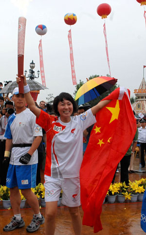 Torchbearer Wang Junxia gestures with national flag during the 2008 Beijing Olympic Games torch relay in Dalian, city of northeast China's Liaoning Province, on July 19, 2008. 