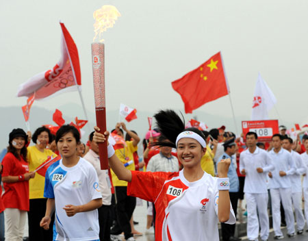 Torchbearer Liu Wenxin runs with the torch during the 2008 Beijing Olympic Games torch relay in Dalian, city of northeast China's Liaoning Province, on July 19, 2008. 