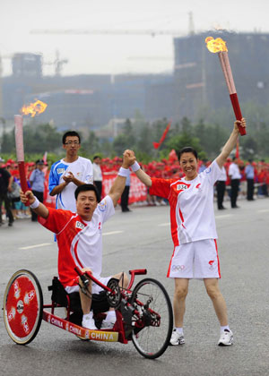 Torchbearer Xu Yongjiu(R) and the successor Ji Bin display the torches during the 2008 Beijing Olympic Games torch relay in Dalian, city of northeast China's Liaoning Province, on July 19, 2008.