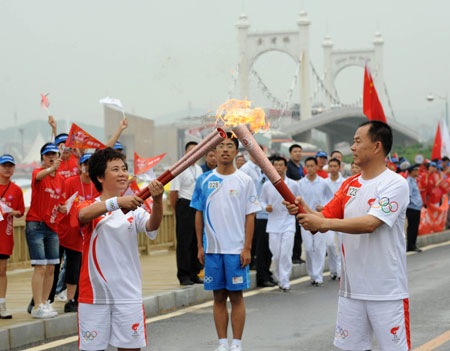 Torchbearer Qi Chunsheng(R) lights torch for the successor Qiao Zhiying during the 2008 Beijing Olympic Games torch relay in Dalian, city of northeast China's Liaoning Province, on July 19, 2008. 