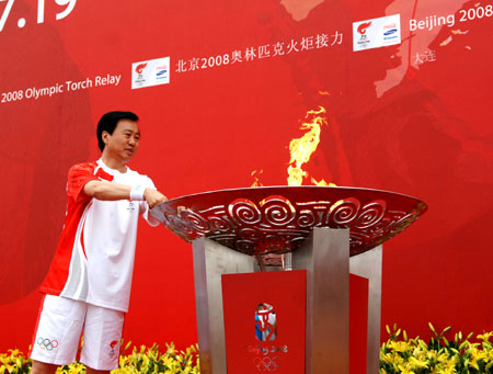 Torchbearer Xia Deren lights the Olympic flame basin during the 2008 Beijing Olympic Games torch relay in Dalian, city of northeast China's Liaoning Province, on July 19, 2008. 