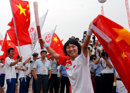 Torchbearer Wang Junxia runs with national flag during the 2008 Beijing Olympic Games torch relay in Dalian, city of northeast China's Liaoning Province, on July 19, 2008. 