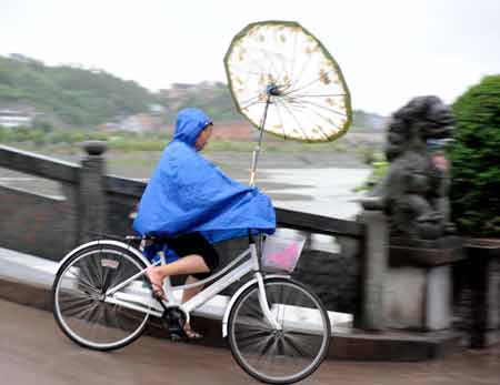  A woman rides her bicycle against the rain in Fuding, east China's Fujian Province, July 18, 2008. 