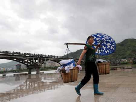 A local carrying goods walks in the rain in Fuding, east China's Fujian Province, July 18, 2008.