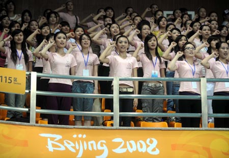 Olympic Games volunteers clench their fists as they recite a pledge to 'serve with honour' during a conference to display sport presentations and awarding ceremonies of the 2008 Beijing Olympic Games in the gym of Beijing Institute of Technology in Beijing, on July 20, 2008.(Xinhua Photo)