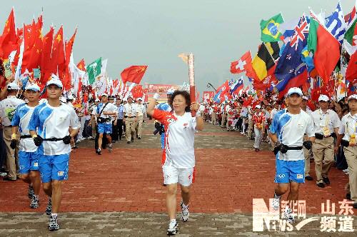 The first torchbearer, Zhang Xiaodong runs with the Olympic torch in Qingdao, Shandong Province July 21.