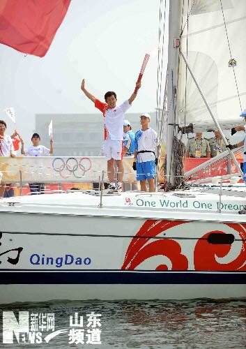 Torchbearer Liu Wei carries the Olympic torch on a sailing boat in Qingdao, Shandong Province July 21. 