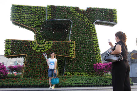 Tourists take photo of a parterre in a form of traditional Chinese dress in Beijing, capital of China, on July 16, 2008. 