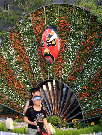 Photo taken on July 15, 2008 shows the parterre forming a fan and Peking Opera mask on the Ping'an Road of Beijing, capital of China.