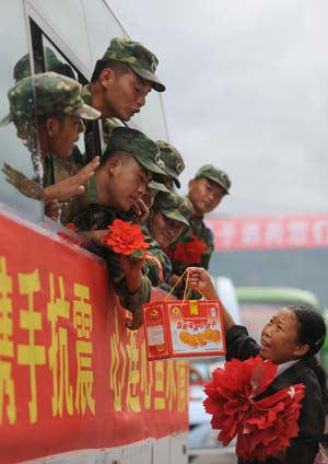  A local villager presents a box of biscuits to express her thanks to the People's Liberation Army (PLA) soldiers when they are leaving the quake-hit Yinghua Town in Shifang City of southwest China's Sichuan Province, July 21, 2008. 