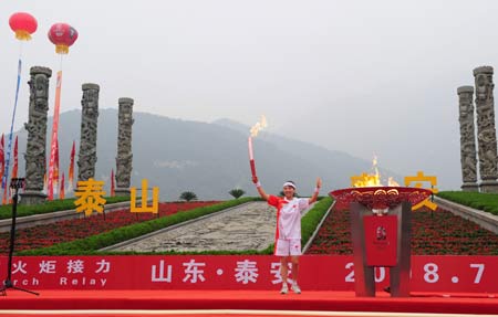 Torchbearer Bi Wenjing displays the torch before lighting the cauldron during the 2008 Beijing Olympic Games torch relay in Tai'an, a city of east China's Shandong Province, on July 22, 2008. 