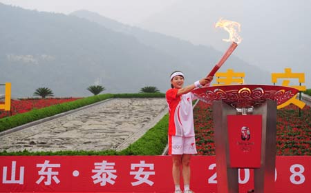 Torchbearer Bi Wenjing lights the cauldron during the 2008 Beijing Olympic Games torch relay in Tai'an, a city of east China's Shandong Province, on July 22, 2008. 