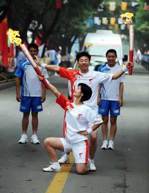  Torchbearer Song Zhiguo (C) gestures with next torchbearer Kong Xinyuan during the 2008 Beijing Olympic Games torch relay in Tai'an, a city of east China's Shandong Province, on July 22, 2008.