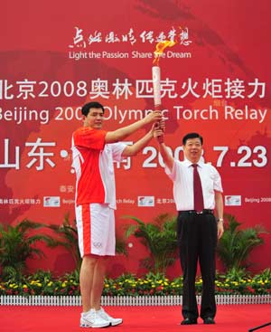 The Olympic torch was relayed in Jinan, capital city of Shandong Province on July 23, 2008. The first torchbearer Gong Xiaobin (L) receives the torch at the launching ceremony.