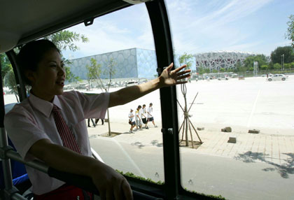 A tour guide talks to passengers on a sightseeing double-deck bus Line 2, which passes Olympic venues such as the National Stadium and National Aquatic Center, July 17, 2008. The other bus Line 1 has the theme of 'Ancient City' and goes by such historical areas as the Temple of Heaven, Tian'anmen Square, and Forbidden City.