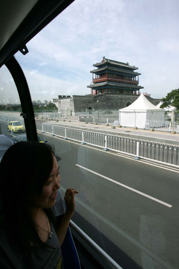 A passenger looks out of the window of the sightseeing double-deck bus Line 2, which passes Olympic venues such as the National Stadium and National Aquatic Center, July 17, 2008. The other bus Line 1 has the theme 'Ancient City' and goes by such historical areas as the Temple of Heaven, Tian'anmen Square, and Forbidden City.