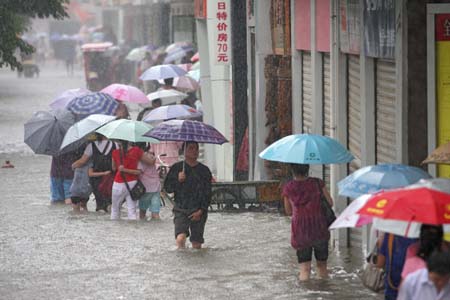 Pedestrians wade on a flooded road in Xiangfan City, central China's Hubei Province, July 22, 2008. A heavy rain hit the city Tuesday causing some roads flooded. The local PLA soldiers and officers have thrown themselves into the fight against the floods. (Xinhua/Yu Xiang)