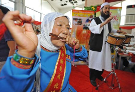 Ma Lanhua, inheritor of one of China's Intangible Cultural Heritages, named Ma's Kouxian, which is a traditional musical instrument played by mouth, gives her performance during the first Ningxia Culture Travel Products Show in Yinchuan, capital of northwest China's Ningxia Hui Autonomous Region, July 23, 2008. As the first of its kind, the exposition kicked off on Wednesday, presenting visitors folk-custom culture performances, special local products sale, arts and calligraphy shows and other kinds of programs.