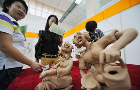 Visitors view clay art works during the first Ningxia Culture Travel Products Show in Yinchuan, capital of northwest China's Ningxia Hui Autonomous Region, July 23, 2008. 