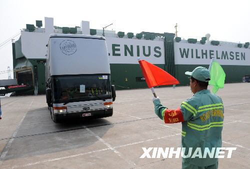 Dock workers are directing the vans when they are getting off the ship.