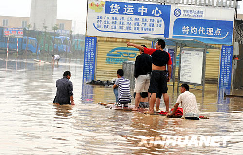 7月24日，几位襄樊市民乘自制的木筏涉水前行。从7月22日凌晨起，湖北襄樊全市遭受特大暴雨袭击。截至24日18时，全市有81个乡镇108万多人受灾，转移安置受灾群众8万多人。目前，部分乡镇仍未恢复通讯，灾情在进一步扩大。 新华社记者 余国庆 摄