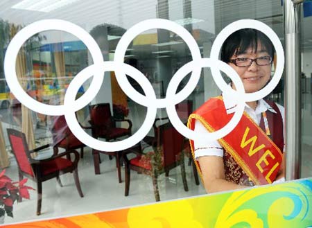 A receptionist smiles at an entrance to the media village for the Beijing 2008 Olympic Games in Beijing, July 25, 2008.
