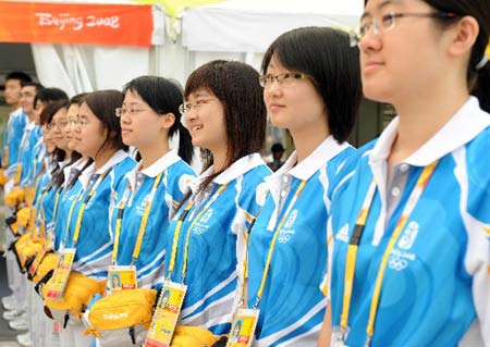 Volunteers stand at an entrance to the media village for the Beijing 2008 Olympic Games in Beijing, July 25, 2008. The media center opens on Friday to journalists from all around the world.