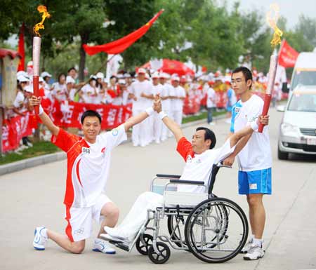 Torchbearer Ma Ruilai (C) poses with the next torchbearer Liu Tao during the 2008 Beijing Olympic Games torch relay in Kaifeng, central China's Henan Province, July 26, 2008. 