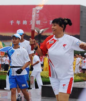 Torchbearer Zheng Haixia runs with the torch during the 2008 Beijing Olympic Games torch relay in Kaifeng, central China's Henan Province, July 26, 2008. 
