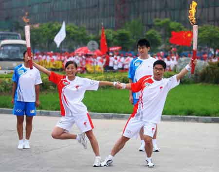 Torchbearer Shang Yongbo (R) poses with the next torchbearer Gao Yingna during the 2008 Beijing Olympic Games torch relay in Kaifeng, central China's Henan Province, July 26, 2008.