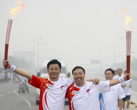 Torchbearer Wang Shunqi (L) poses with the next torchbearer Wu Hong during the Beijing 2008 Olympic Games torch relay in Anyang, central China's Henan Province, July 28, 2008. 