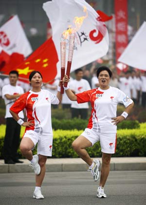 Torchbearer Zhang Meiying (R) poses with the next torchbearer Zhang Junying during the Beijing 2008 Olympic Games torch relay in Anyang, central China's Henan Province, July 28, 2008. 