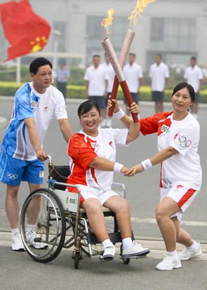 Torchbearer Zhang Junying (R) poses with the next torchbearer Jia Hong during the Beijing 2008 Olympic Games torch relay in Anyang, central China's Henan Province, July 28, 2008. 
