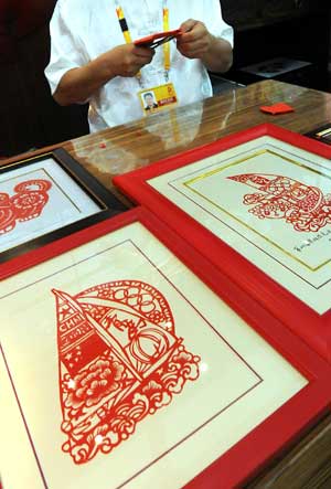 A handicraft artist makes paper-cutting works at the folk customs culture exhibition in the Qingdao Olympic village in Qingdao, the co-host city for sailing events of the Beijing 2008 Olympic Games, in east China's Shandong Province, July 27, 2008. 