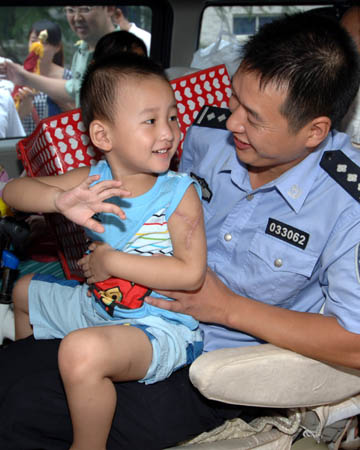 Lang Zheng (L), known as the "Salute Boy", leaves Tangdu Hospital in the arms of his father Lang Hongdong after two months of treatment, in Xi
