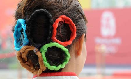 A volunteer wear a five-ring hair spin at Olympic Village in Beijing.