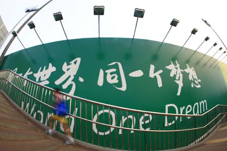 A boy runs past a poster board which reads &apos;One world, one dream&apos;, the slogan of the Beijing Olympic Games July 26, 2008.