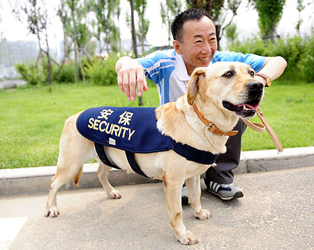 A security guard poses with his sniffer dog at the Beijing Olympic Village, July 27, 2008. A total of 204 trained dogs will be used to detect suspicious goods in competition venues, training areas and Olympic-related hospitals and hotels in order to ensure safety during the Olympic and Paralympic Games.