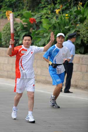 Torchbearer Ren Huifeng (L) holds up the torch during the Beijing 2008 Olympic Games torch relay in Shijiazhuang, capital of north China's Hebei Province, July 29, 2008. 