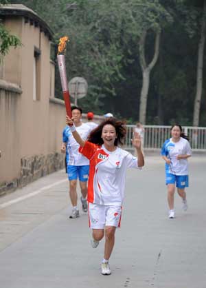 Torchbearer Wang Xiaojie (front) holds up the torch during the Beijing 2008 Olympic Games torch relay in Shijiazhuang, capital of north China's Hebei Province, July 29, 2008. 