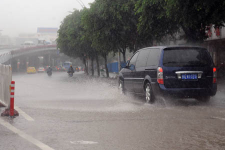 Vehicles splash through a flooded street in Fuzhou City, capital of southeast China's Fujian Province, July 28, 2008. Typhoon Fung Wong, which was lashing Taiwan on Monday morning, continued to strengthen as it headed toward the southeastern coast of mainland China, according to the observatory of Fujian Province. (Xinhua/Jiang Kehong)